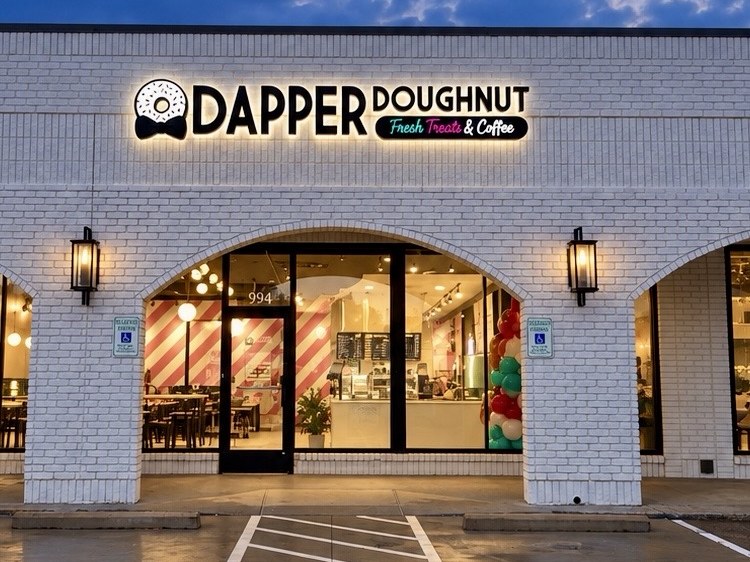 Dapper Doughnut storefront at 994 N Cooper St, Arlington, Texas, lit up at dusk with grand-opening balloons.